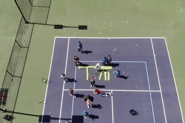 A group of people standing on top of a tennis court.