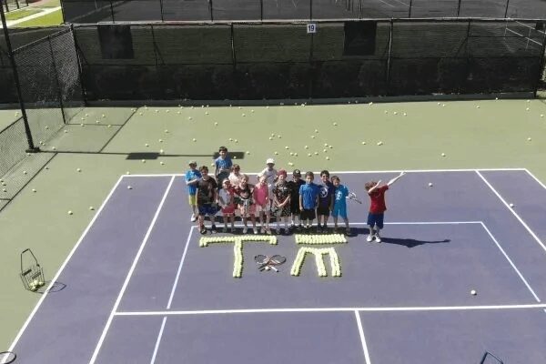 A group of people standing on top of a tennis court.