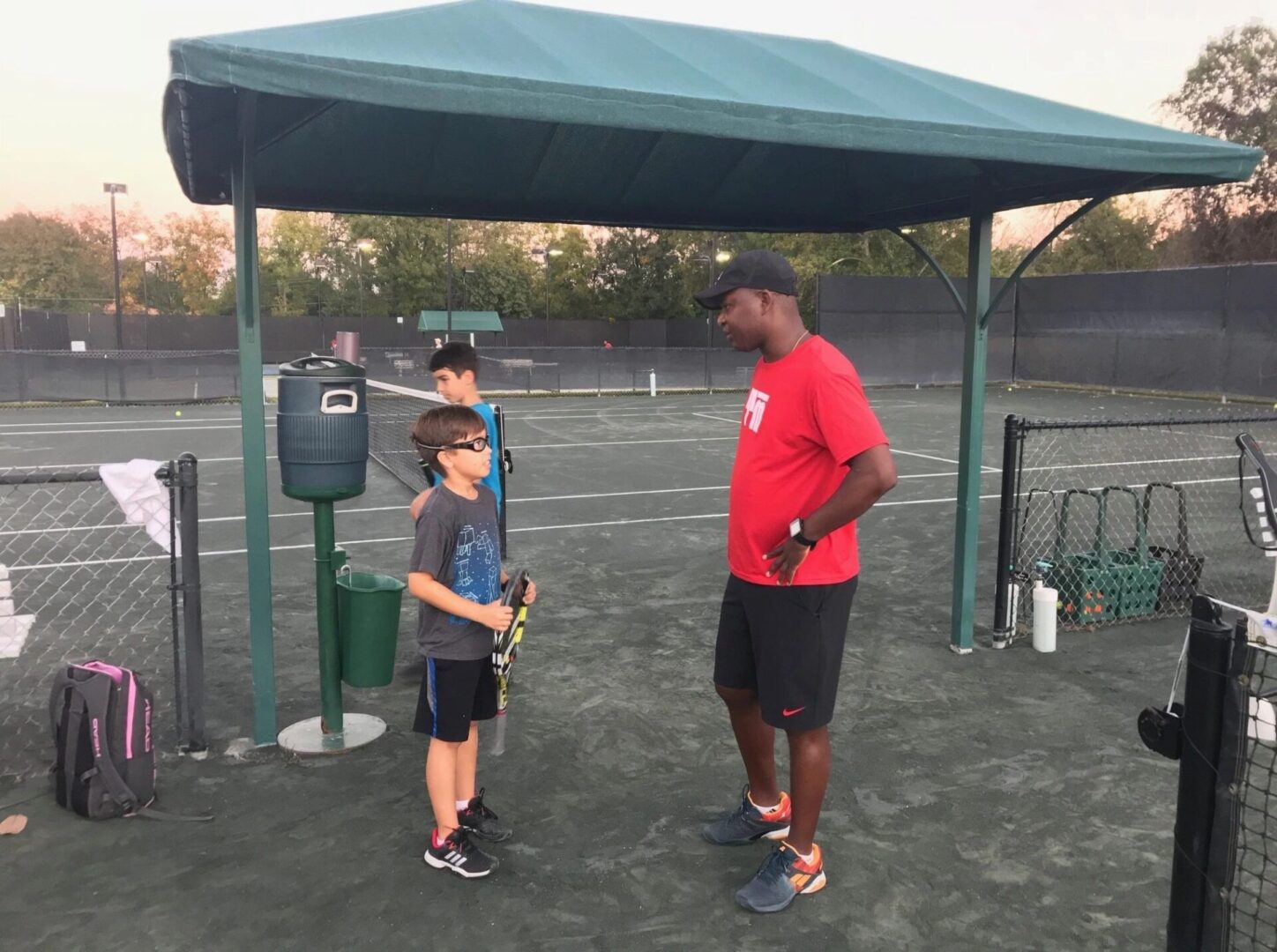 A man and boy are standing on the tennis court.