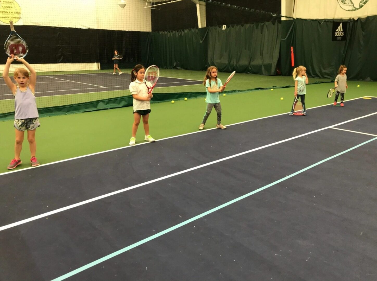 A group of children playing tennis on the court