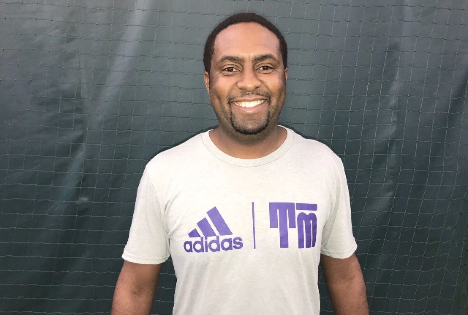 A man in white shirt standing next to green wall.