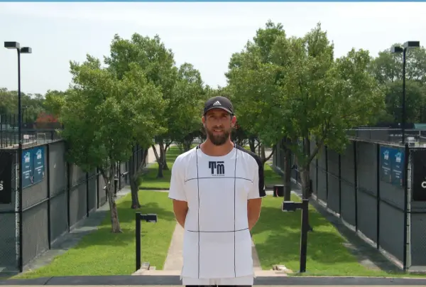 A man standing in front of a fence.