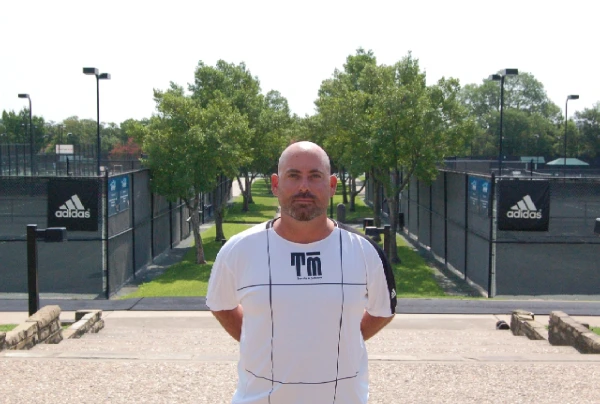 A man standing in front of a fence.